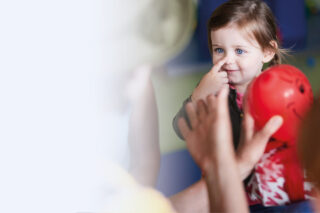 Ein kleines Mädchen macht eine Konzentrationsübung, tippt sich auf die Nase.