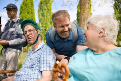 Menschen mit und ohne Behinderung sind als Gruppe unterwegs, lachen gemeinsam.