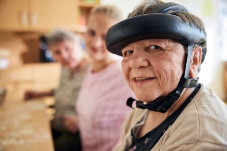 Eine Seniorin backt in der Gruppe Plätzchen, lächelt freundlich in die Kamera.