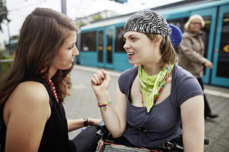 Jungen Frauen sind gemeinsam unterwegs, warten auf einem Bahnsteig.