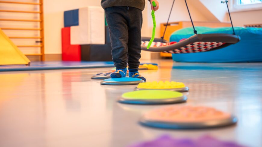 Kinderfüße und ein Parcours auf Turnhallenboden.