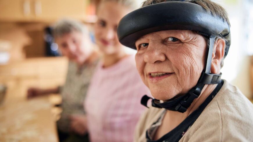 Eine Seniorin backt in der Gruppe Plätzchen, lächelt freundlich in die Kamera.